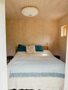 a bedroom with a white bed with a wooden wall at Modern Family Home In Ängelsbäcksstrand in Båstad