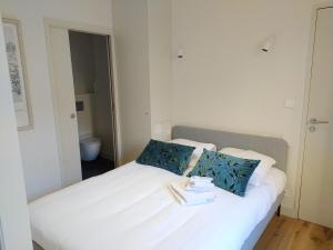 a white bed with blue pillows in a room at Appartement neuf centre historique in Bordeaux