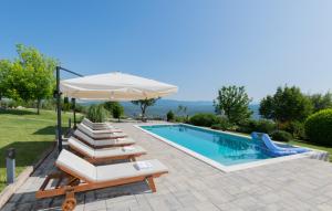 een zwembad met ligstoelen en een parasol bij Villa Piplica-Makarska by Villas Guide in Ujevići
