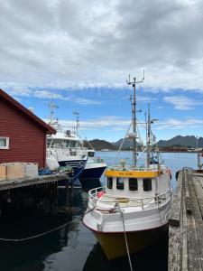 three boats docked at a dock with a red building at The Angler's House in Ballstad