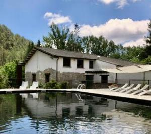 a house with a swimming pool and some white chairs at Acogedora casa en la montaña in La Baronia de Rialb