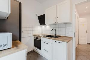 une cuisine avec des armoires blanches et un évier dans l'établissement Dessaus Motto Appartements! Solo - Pärchen - Familien - Gruppen, à Dessau