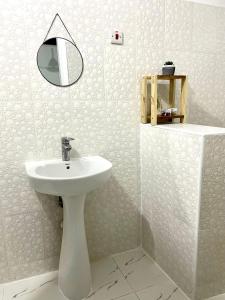 Un baño blanco con lavabo y espejo. en Palm & Earth Rooms, en Jambiani