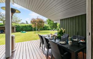 a wooden deck with a table and chairs at 4 Bedroom Awesome Home In Otterup in Otterup +9 photos