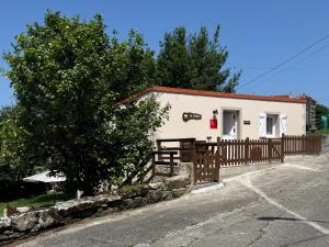 a small white building with a fence and a tree at As Cortiñas, casa vacacional completa en Laxe 