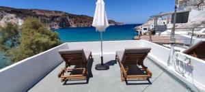 two chairs and an umbrella on a balcony with the ocean at Salty Kisses and Sandy Toes in Firopótamos