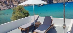 two chairs and an umbrella on a balcony with the ocean at Salty Kisses and Sandy Toes in Firopótamos