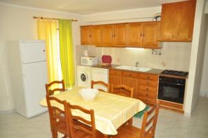 a kitchen with a table and chairs and a white refrigerator at Casa Anabela - Beach Apartment in Lourinhã