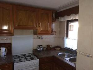 a kitchen with wooden cabinets and a stove and a sink at Casa Caetano in Souto da Carpalhosa +6 photos