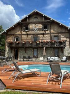 a house with a pool and two chairs in front of it at Maison La Devinière - sauna et spa compris accessibles toute l'année in Xonrupt-Longemer