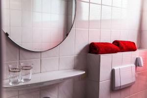 ein Badezimmer mit einem Spiegel und roten Handtüchern auf einem Regal in der Unterkunft Dünenglück, Ferienwohnung 33 in Cuxhaven