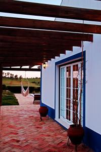 a blue and white building with a window and a hammock at O Monte do Alhinho - Turismo Rural in Monte Costa