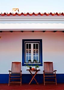 two chairs and a table in front of a window at O Monte do Alhinho - Turismo Rural in Monte Costa
