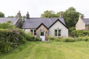 a white house with a white door in a yard at Pentland Cottage in Norham