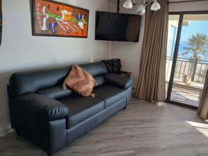 a black leather couch in a living room with a television at Department la Serena Beach in La Serena