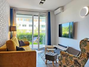 a living room with a couch and a tv at Apartament Sand&Blue z basenem in Sztutowo