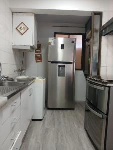 a kitchen with a stainless steel refrigerator and white cabinets at Department la Serena Beach in La Serena