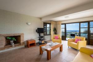 a living room with yellow chairs and a fireplace at Villa Athina in Kalathos