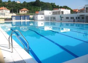 a large swimming pool with blue water and buildings at Studio Apartmani Kaja i Iva in Sinj