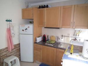 a kitchen with a white refrigerator and wooden cabinets at Manuel Terrace House in Alvor +19 photos