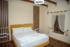 um quarto com uma cama com lençóis brancos e uma janela em Vila Beleri 