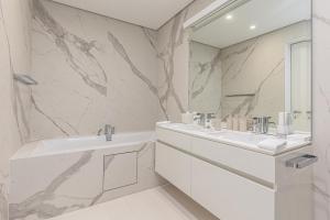a white bathroom with two sinks and a mirror at Dukley Hotel & Resort in Budva