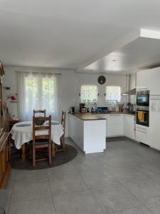 a kitchen with white cabinets and a table and chairs at Maison entre culture et détente in La Celle-Saint-Cloud