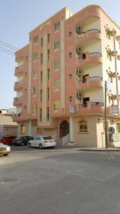 un gran edificio con coches estacionados frente a él en Golden Seasons Furnished Apartment, en Salalah