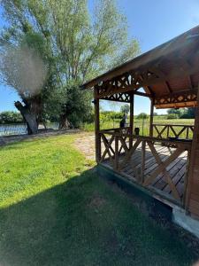 a wooden pavilion in a field with a tree at Ku Jezioru in Pawłowice +20 photos