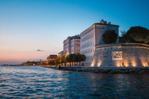Blick auf eine Stadt vom Wasser aus in der Abenddämmerung in der Unterkunft Estium Heritage Rooms in Zadar
