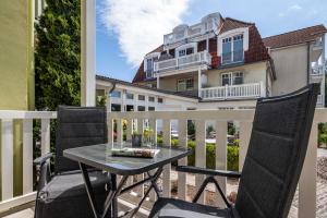 een tafel en stoelen op een balkon met een huis bij App Osiria in Kühlungsborn +10 foto's