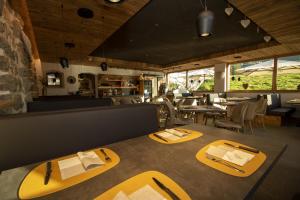 a restaurant with yellow dining tables and chairs at Bar-Restaurant-Pizzeria Antermont B&B in Carezza al Lago