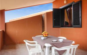 a table with white chairs and a vase of fruit on it at Awesome Apartment In Costa Rei -Ca- With Wifi in Monte Nai
