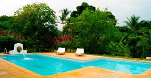 - une piscine avec 2 chaises longues à côté dans l'établissement Pousada Tubarão, à Arraial d'Ajuda
