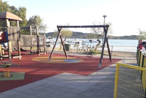 Un parque infantil con columpios junto al agua. en Srima apartments 20 meters from the beach, en Srima