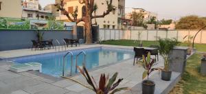 a swimming pool in a backyard with chairs and a table at Sinclairs Udaipur in Udaipur
