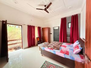 ein Schlafzimmer mit einem Bett und einem Fenster mit roten Vorhängen in der Unterkunft Rameshwari Homestay in Lansdowne