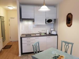 eine Küche mit weißen Schränken und einem Tisch mit Stühlen in der Unterkunft Fewo Rosenhof 13 in Kühlungsborn + 12 Fotos