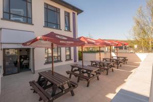a row of wooden benches with umbrellas in front of a building at The Kenmare Bay Hotel & Luxury Lodges Resort in Kenmare +48 photos