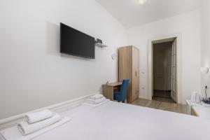 a white room with a bed and a tv on the wall at Fluminis rooms in Rijeka +14 photos
