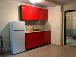 a kitchen with red cabinets and a white refrigerator at Afrodita Apartments 2 in Sinemorets