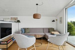 a living room with a couch and chairs and a tv at Newly Renovated Holiday Home With Aarhus Bay Views in Rønde