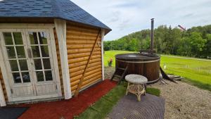 a small cabin with a hot tub and a grill at Järvevaatega Puhkemajake in Nüpli