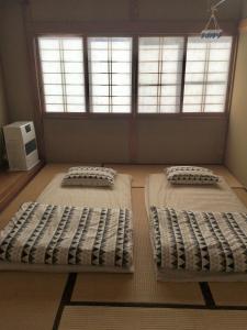 two beds in a room with two windows at Winter Season - 民泊 Matsuo House in Zao Onsen - Japanese Style - Private Room in Zao Onsen +48 photos