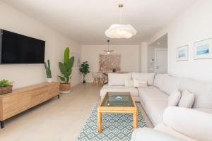 Una sala de estar con un sofá blanco y un televisor. en In front of SEA & CENTER, en Marbella