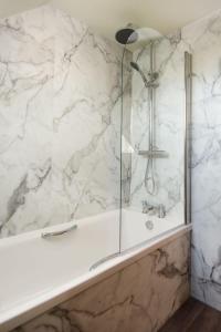 a bathroom with a shower with a white marble wall at Windy Cottage, Coldstream in Coldstream +13 photos