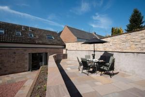 a patio with a table and chairs and an umbrella at Windy Cottage, Coldstream in Coldstream