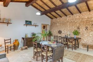 sala de estar con mesa, sillas y pared de piedra en Tenuta Pizzola, en Nociglia