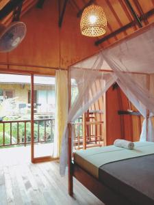 a bedroom with a bed and a large window at Jungle House - surf & stay in Pulukan