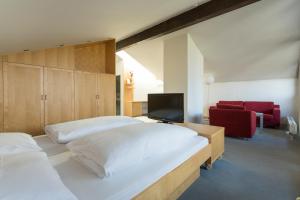 a bedroom with two beds and a tv and a red chair at Isserwirt in Innsbruck